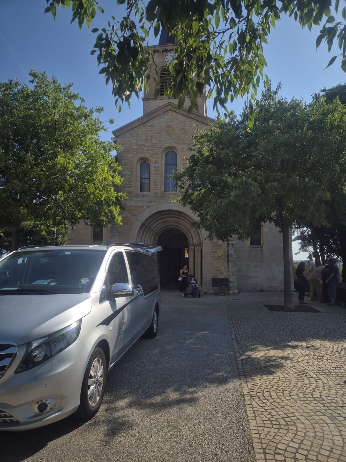 Immeuble aux hautes colonnes ; camionnettes argentées garées dans la rue.