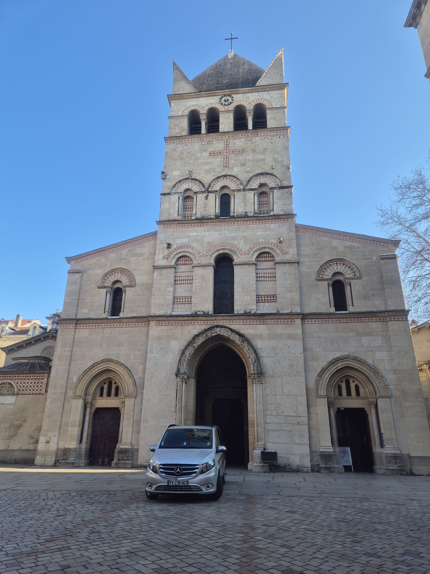 Tombe dans un cimetière avec une pierre tombale grise et des fleurs colorées.