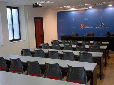 Un aula con mesas y sillas y una pared azul.