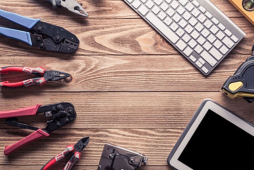 Una mesa de madera cubierta con herramientas, un teclado y una tableta.