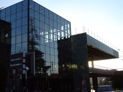 Un gran edificio de cristal con un cartel de estacionamiento enfrente.