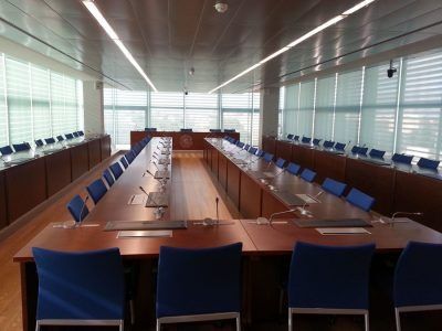 Una sala de conferencias con una mesa larga y sillas azules.