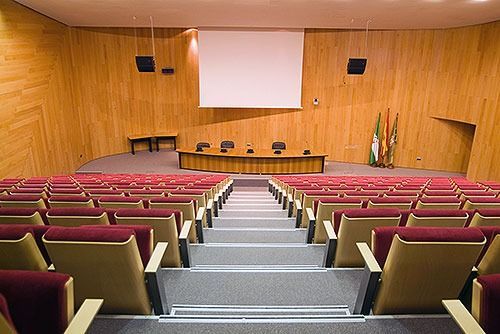 Un gran auditorio con filas de sillas y una pantalla de proyección.