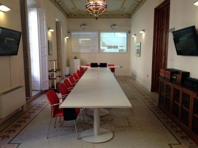 Una sala de conferencias con una larga mesa blanca y sillas rojas.