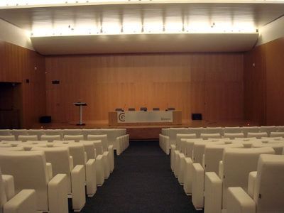 Un gran auditorio con filas de sillas blancas y un escenario.
