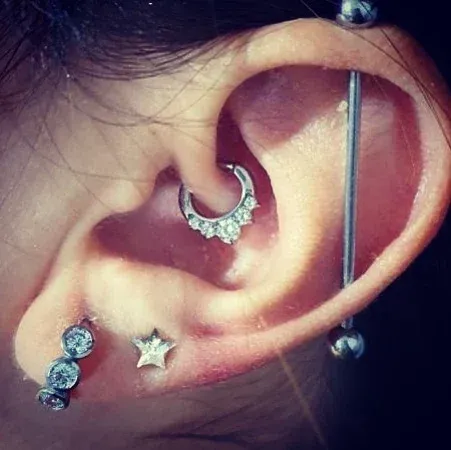 Primer plano de una oreja humana con múltiples perforaciones de color plateado.