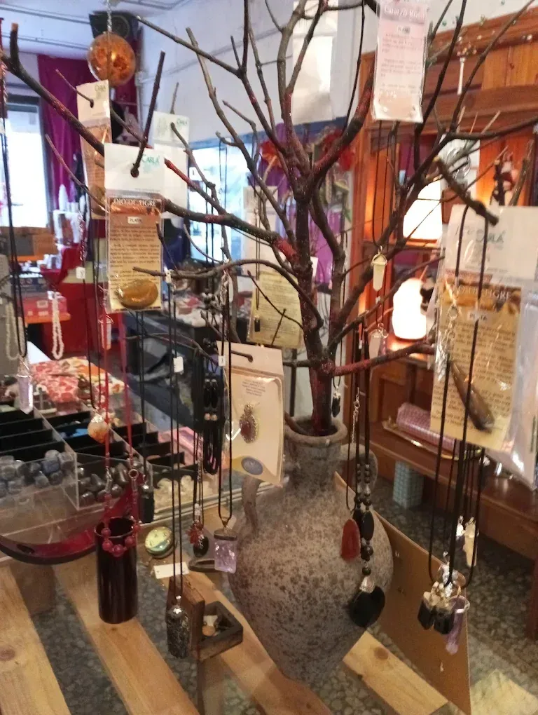 En una tienda, cuelgan collares de las ramas de un árbol decorativo expuesto en el exterior.