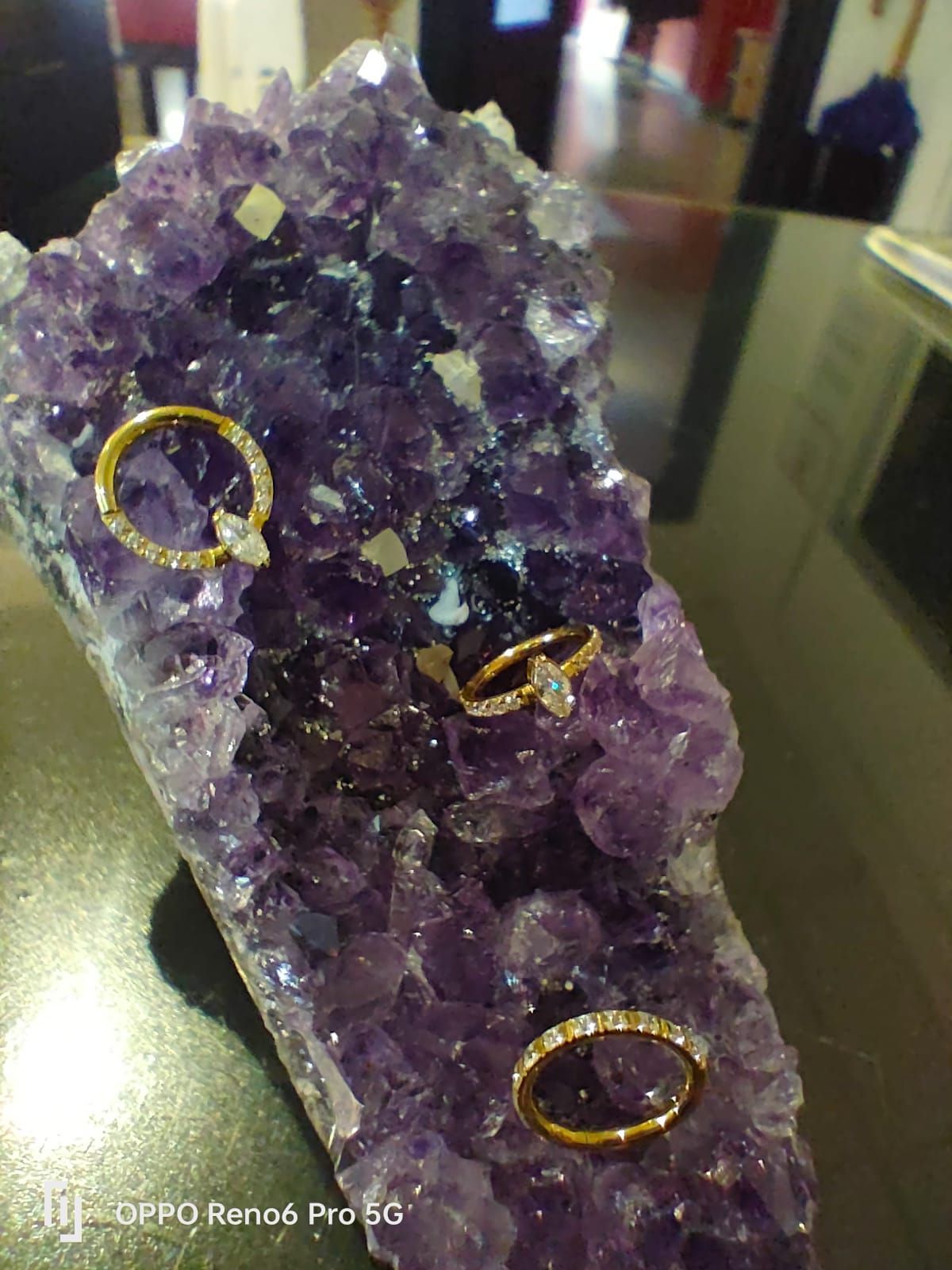 Tres anillos de oro, dos de ellos con piedras talladas en forma de marquesa, expuestos sobre un gran racimo de cristales.