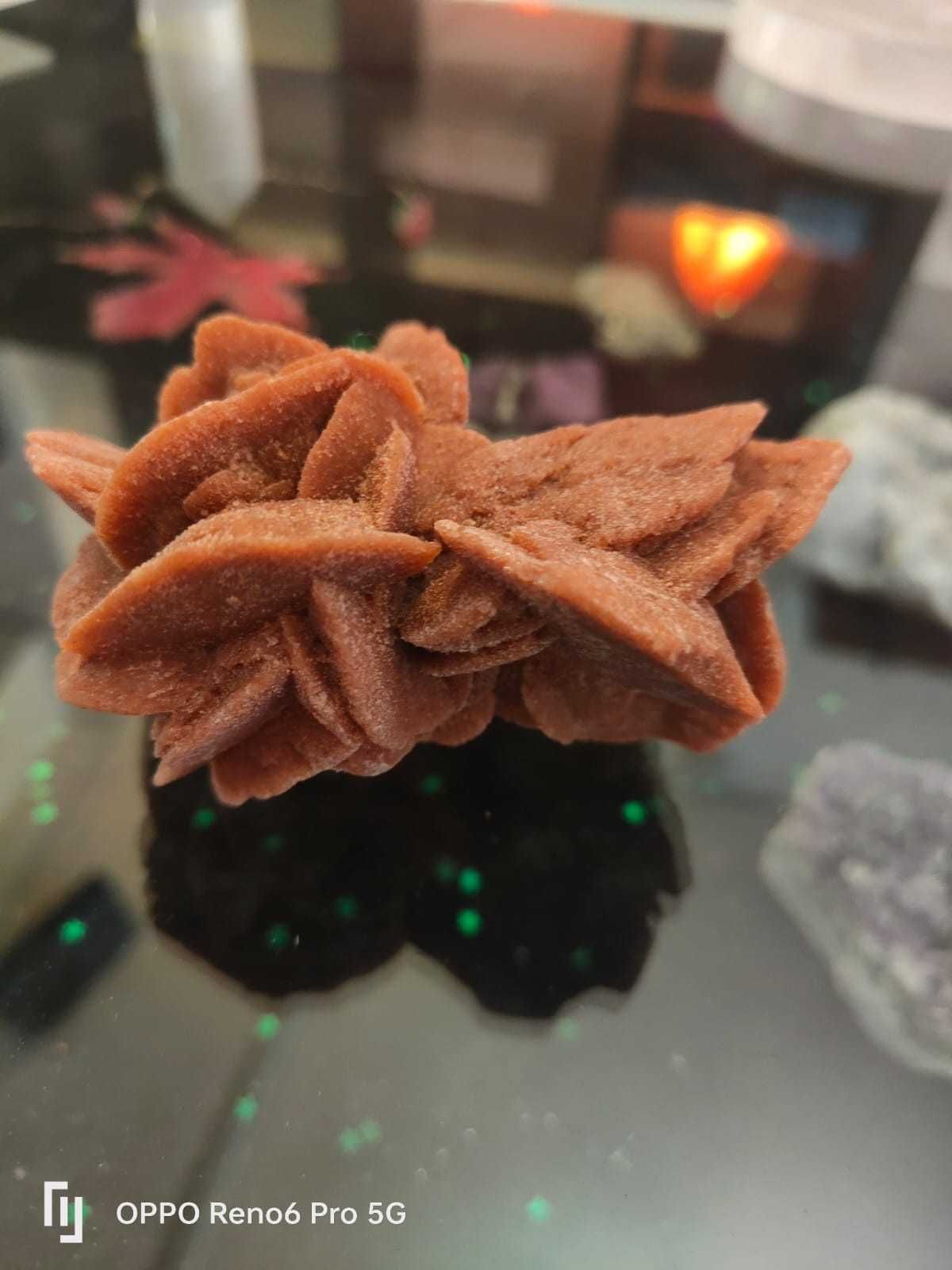 Una formación cristalina de color marrón rojizo, similar a una rosa del desierto, compuesta por capas parecidas a pétalos.