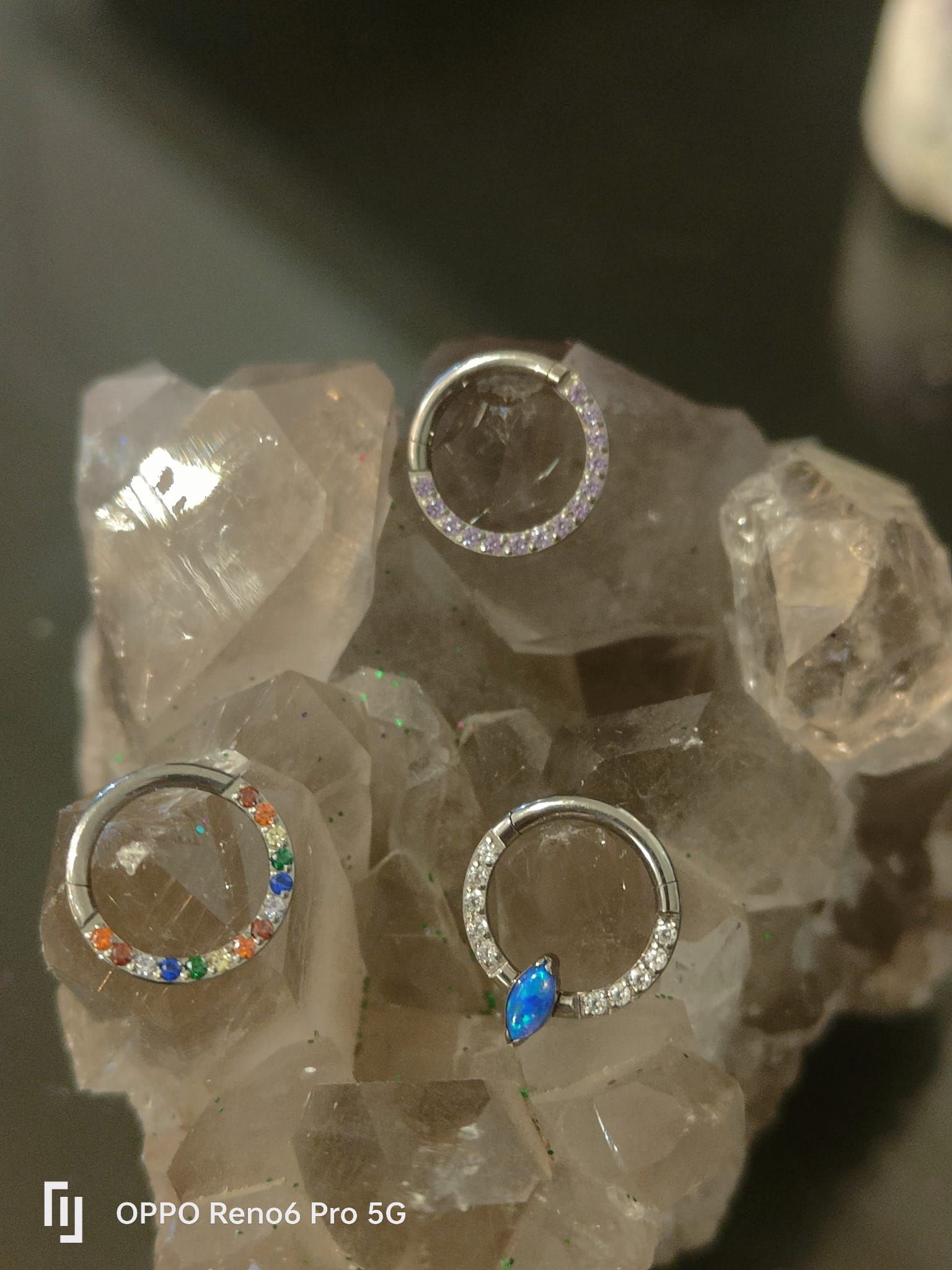 Tres piercings circulares decorativos para el tabique nasal o aros, que descansan sobre un grupo de cristales.