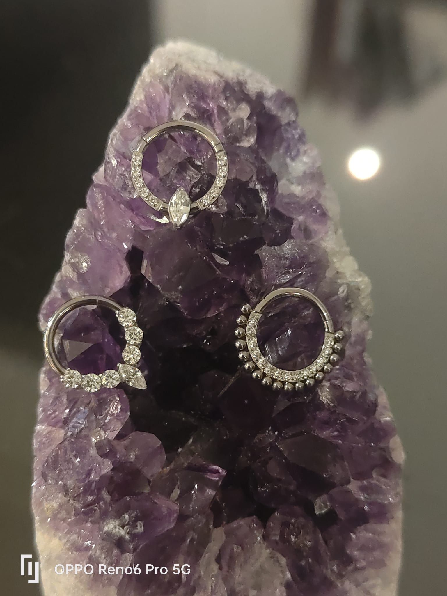 Tres anillos de aro de plata ornamentados con piedras transparentes que descansan sobre un grupo de cristales.