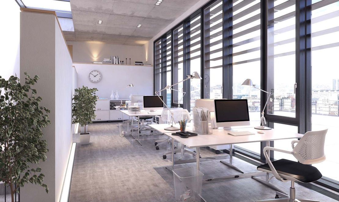 Ein leeres Büro mit vielen Fenstern und Tischen und Stühlen.