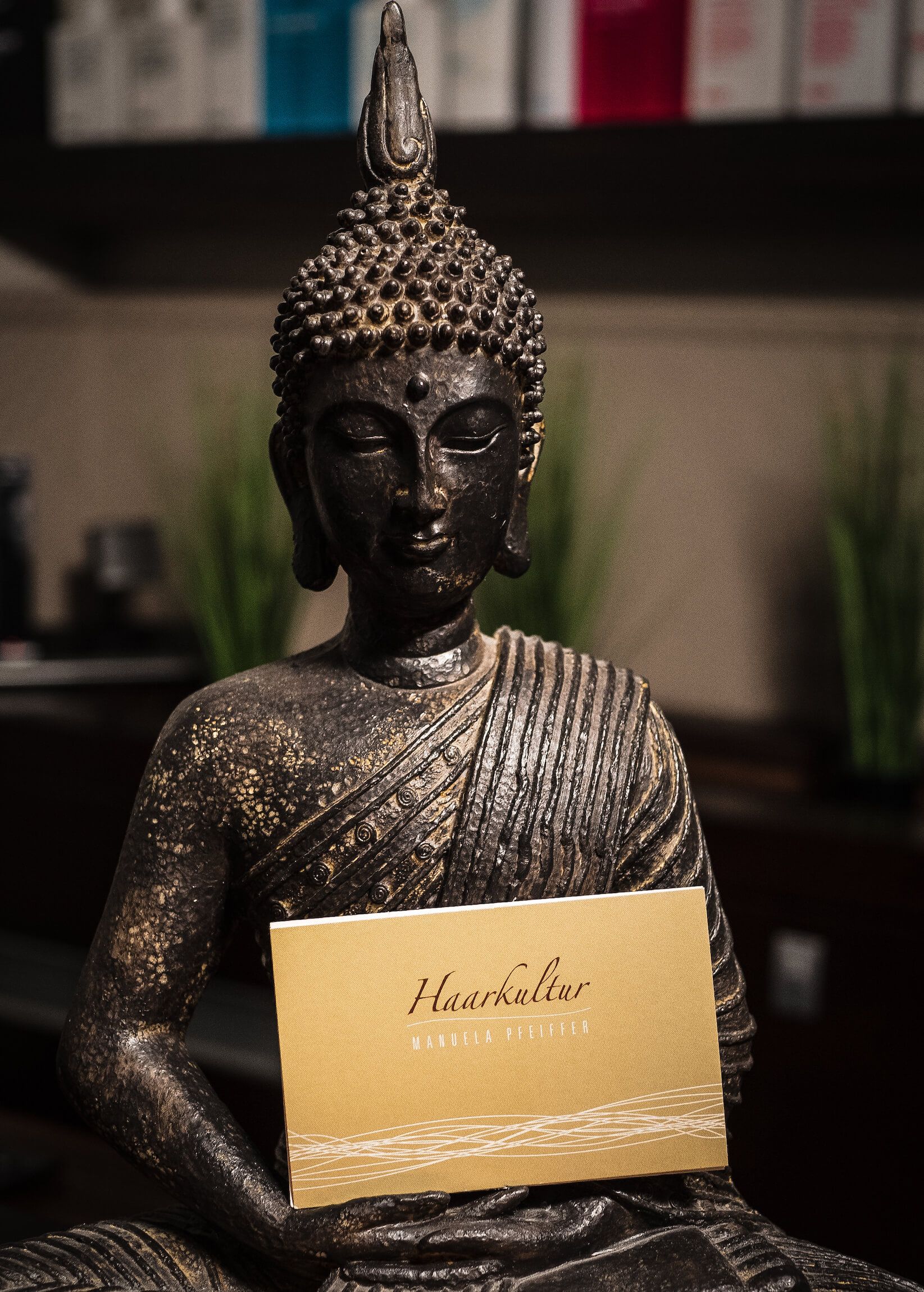 Buddha-Statue, die ein goldenes Schild mit der Aufschrift „Herzlinie“ hält.