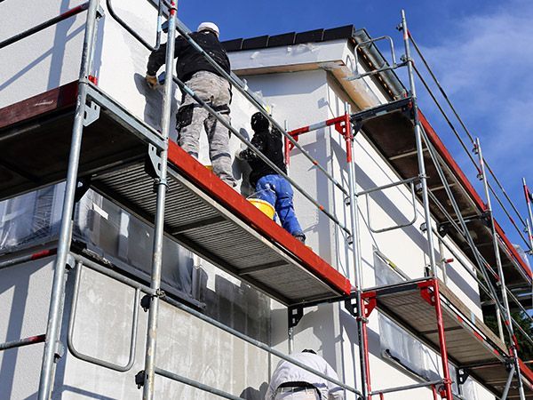 2 ouvriers sur le même échafaudage rénovant une façade