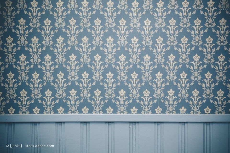 Blaue und cremefarbene Damasttapete über einer blauen, getäfelten Wandvertäfelung.
