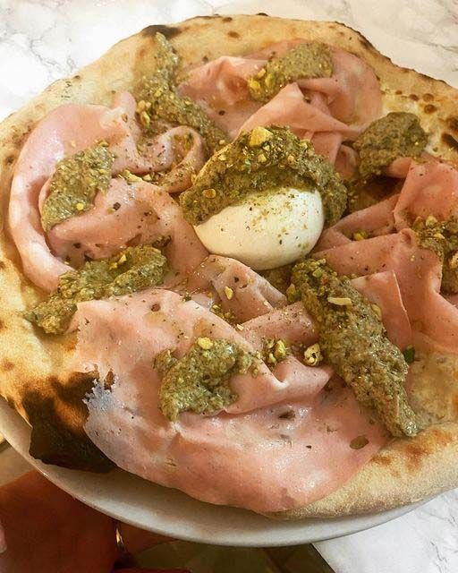 Pizza con mortadela, pesto de pistachos y huevo pasado por agua.