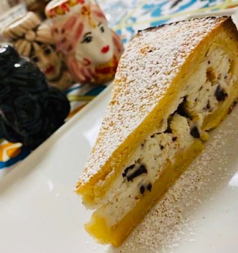 Rebanada de hojaldre rellena de crema y chips de chocolate, espolvoreada con azúcar glas.
