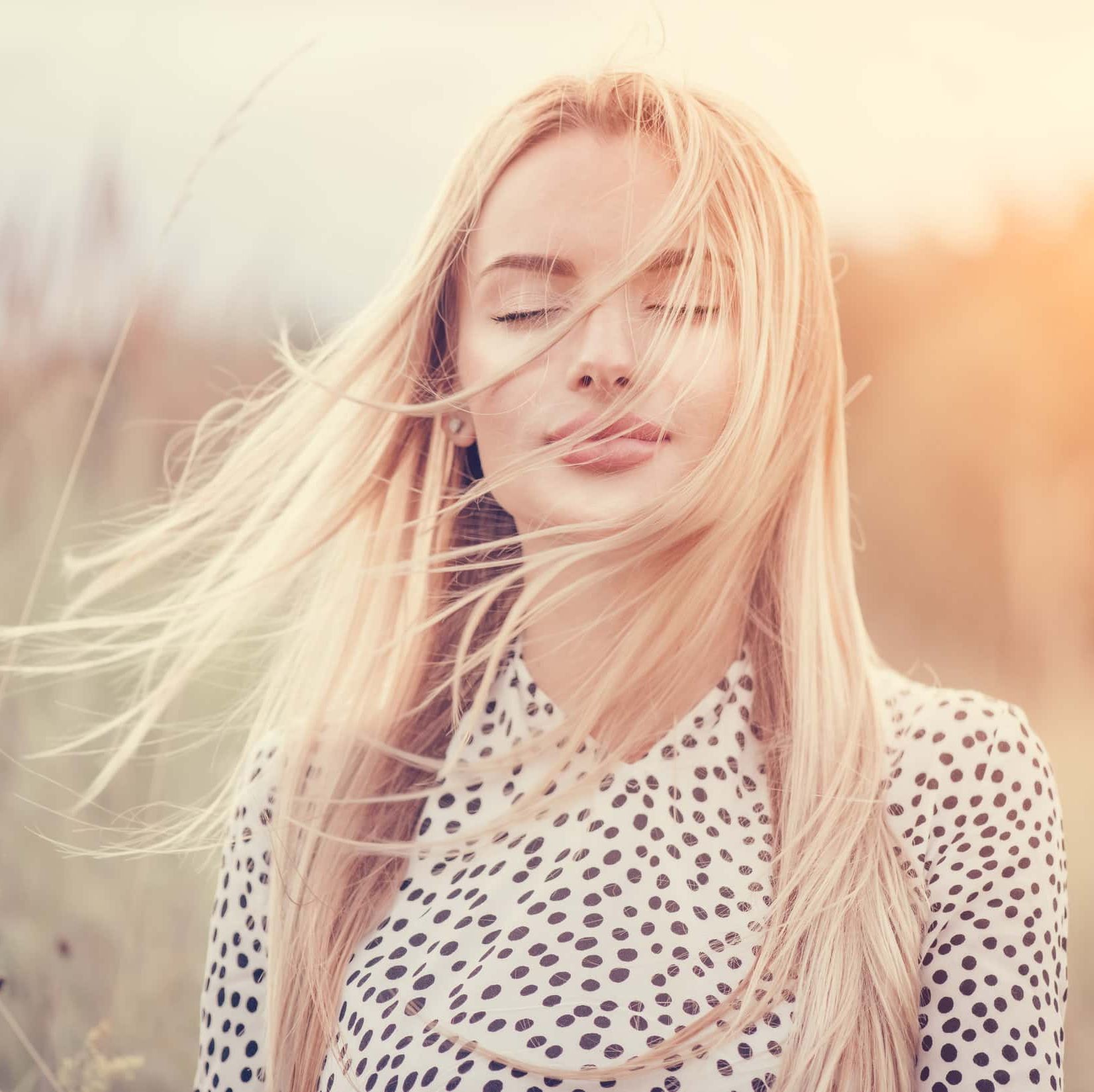 Una mujer con los ojos cerrados y el cabello ondeando al viento.