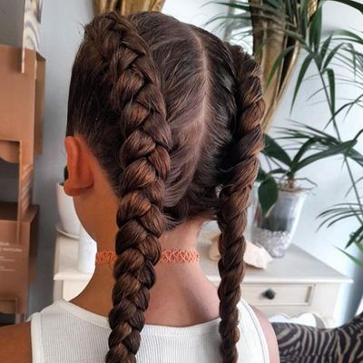 Una chica con dos trenzas en el pelo lleva una camiseta blanca sin mangas.