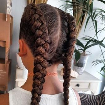 Una chica con dos trenzas en el pelo lleva una camiseta blanca sin mangas.