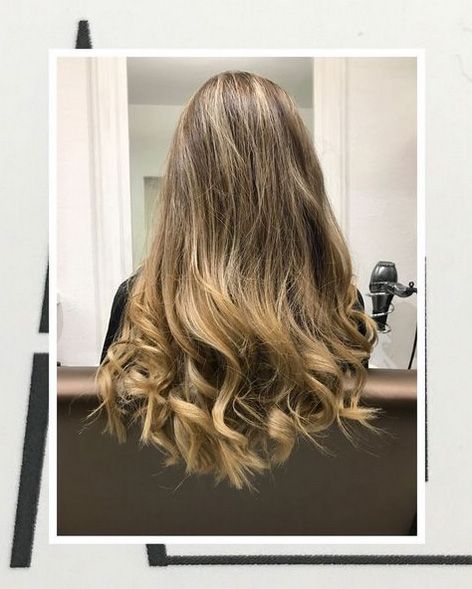 Una mujer con cabello largo y rubio está sentada en una silla frente a un espejo.