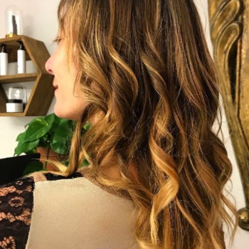 Una mujer con cabello largo y ondulado está parada frente a un espejo.