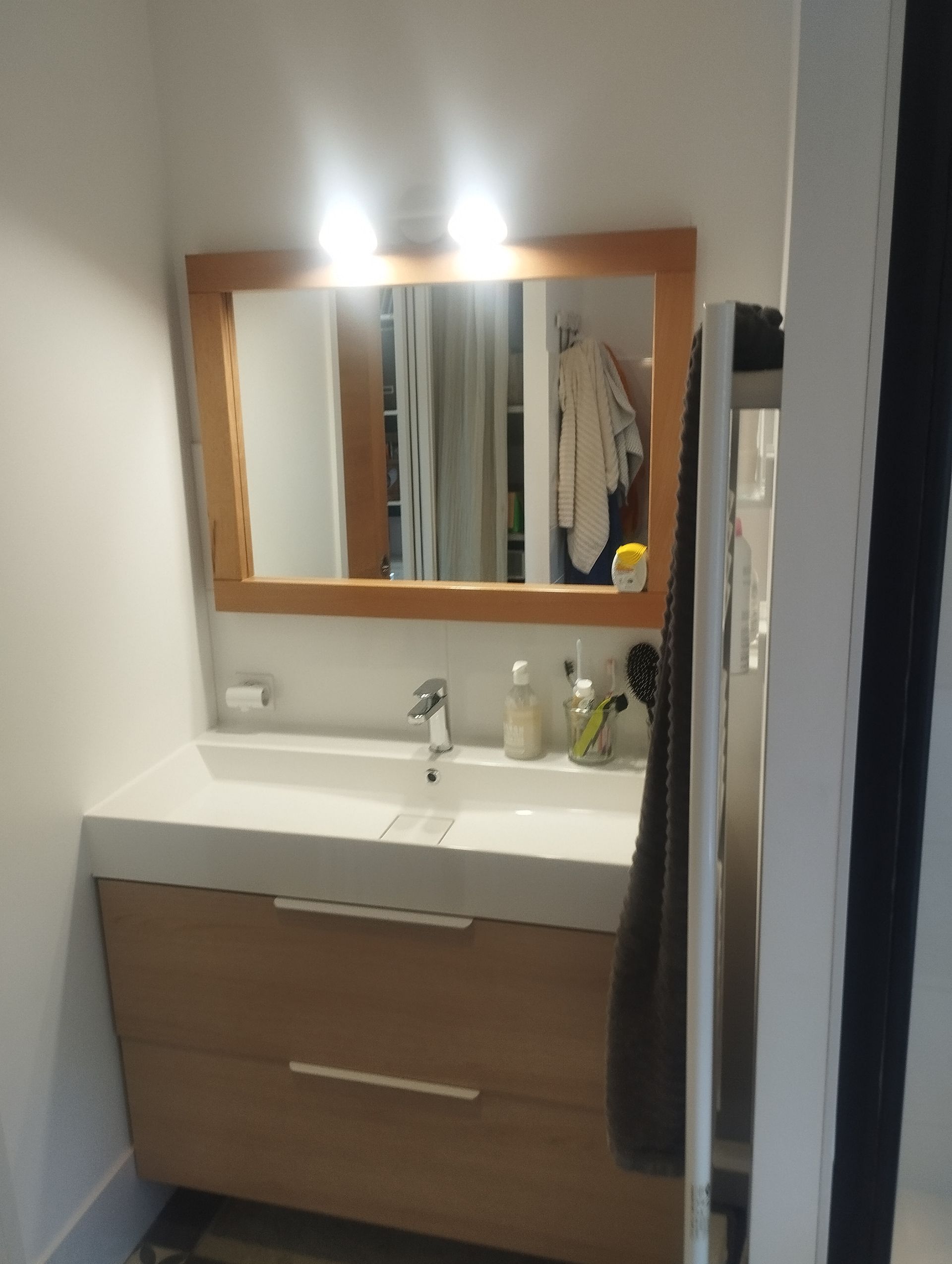 Un évier de salle de bains avec un miroir suspendu.