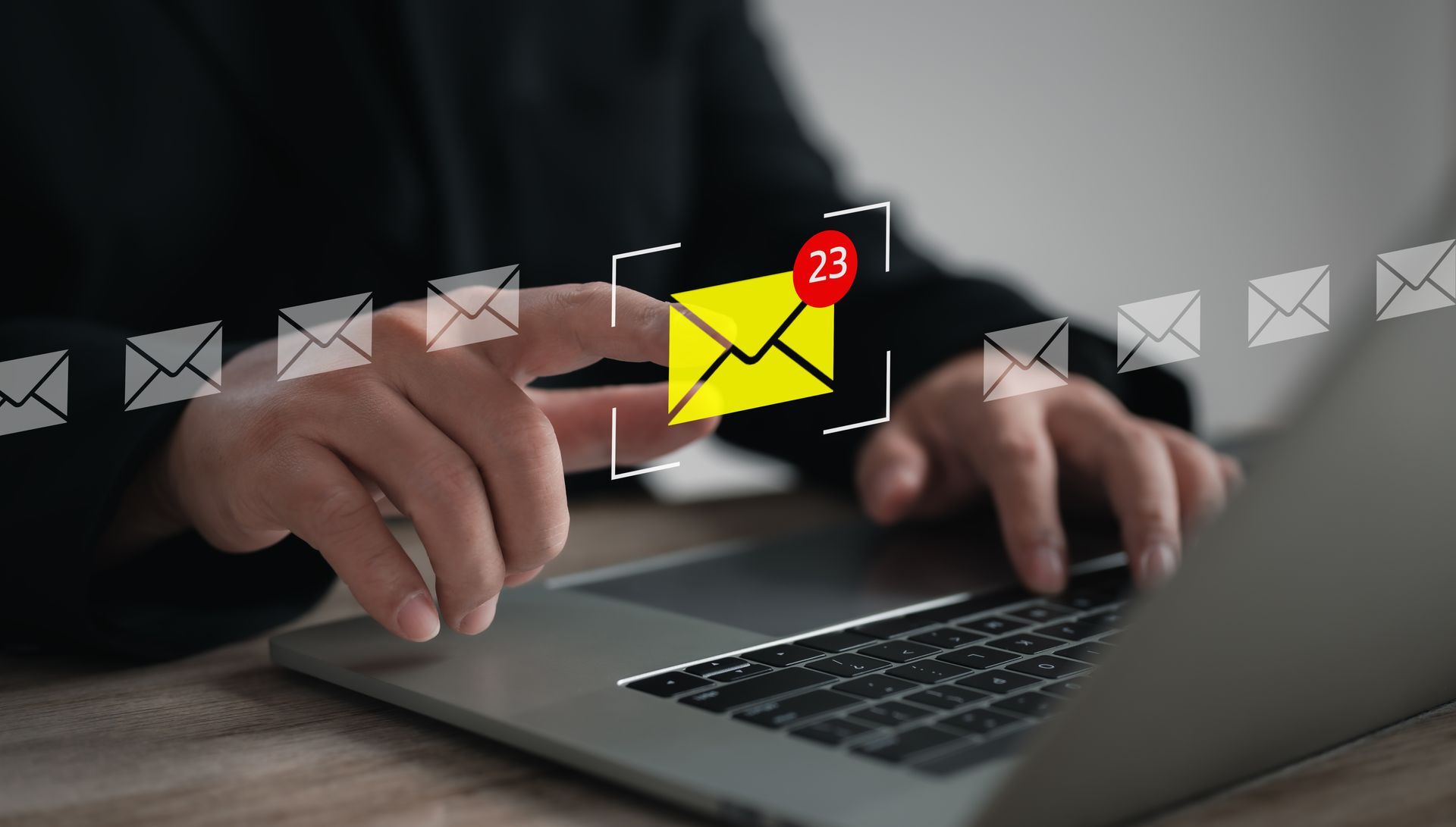 Un homme sur son ordinateur qui écrit un e-mail avec des icônes d'enveloppe qui flottent au-dessus de l'image