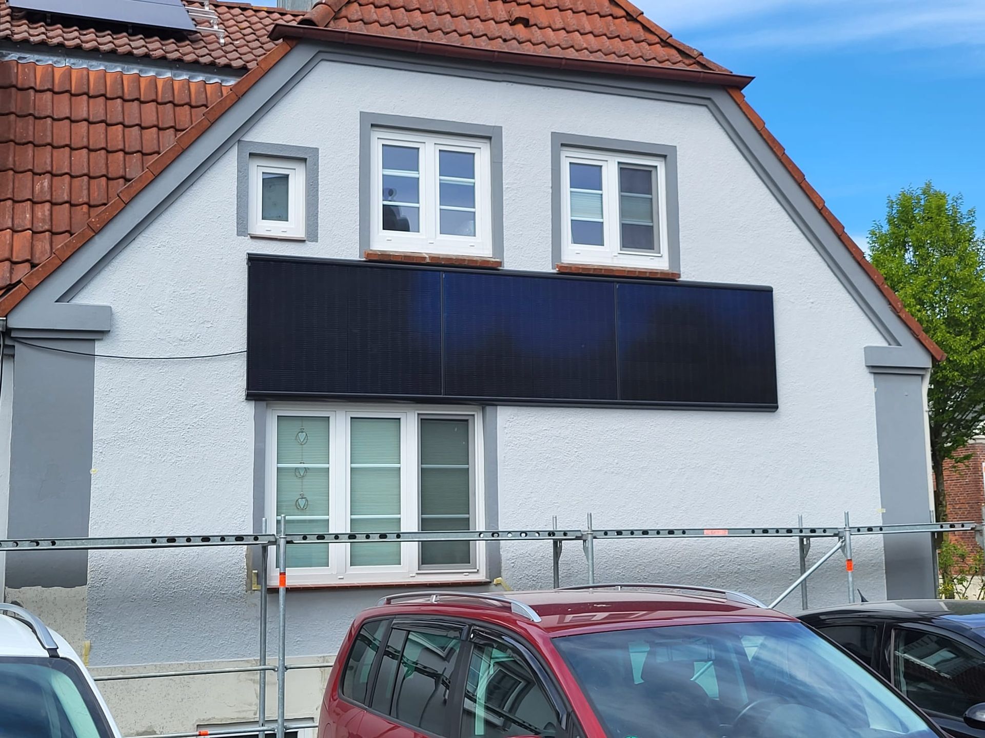 Ein Auto ist vor einem Haus mit Solarmodulen darauf geparkt