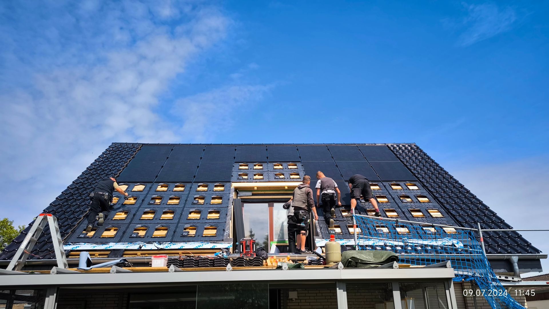 Eine Gruppe von Leuten installiert Solarmodule auf dem Dach eines Hauses.