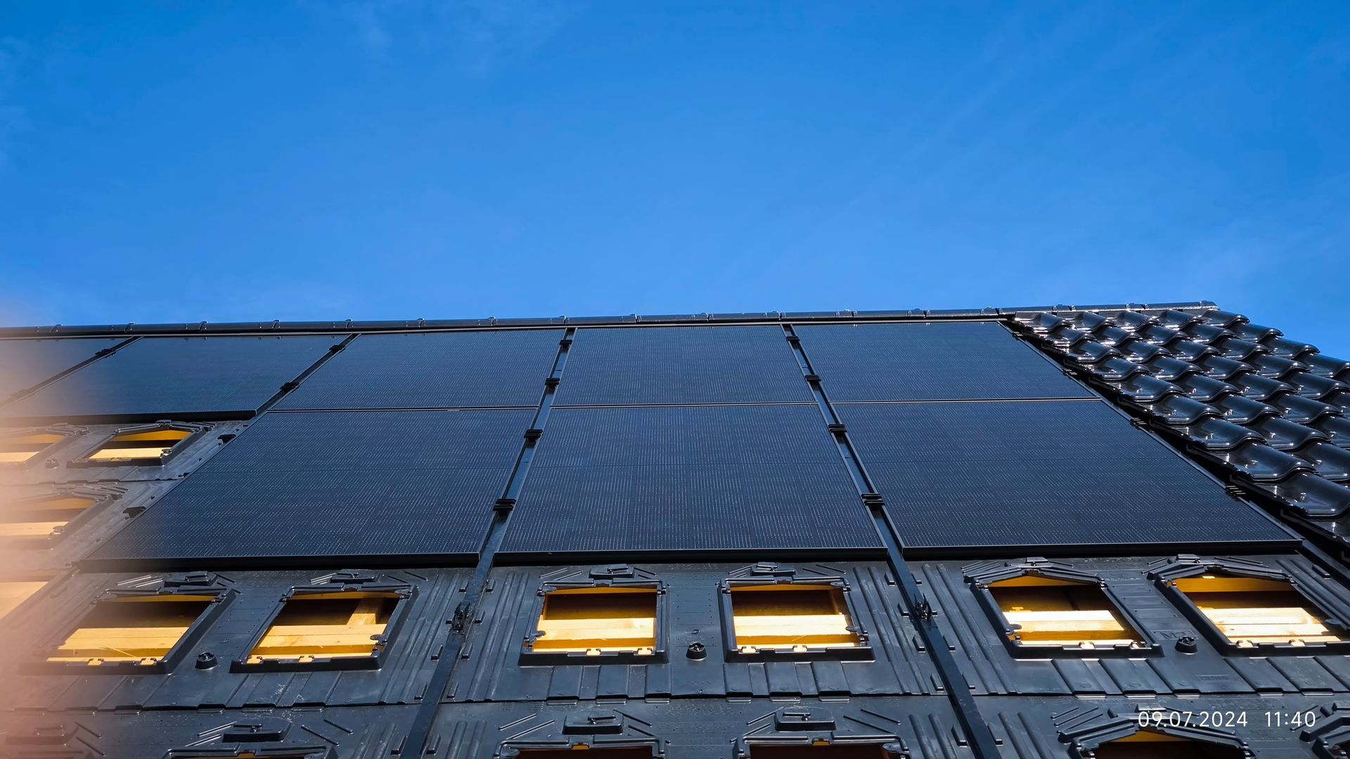 Blick nach oben auf ein Gebäude mit Sonnenkollektoren auf dem Dach