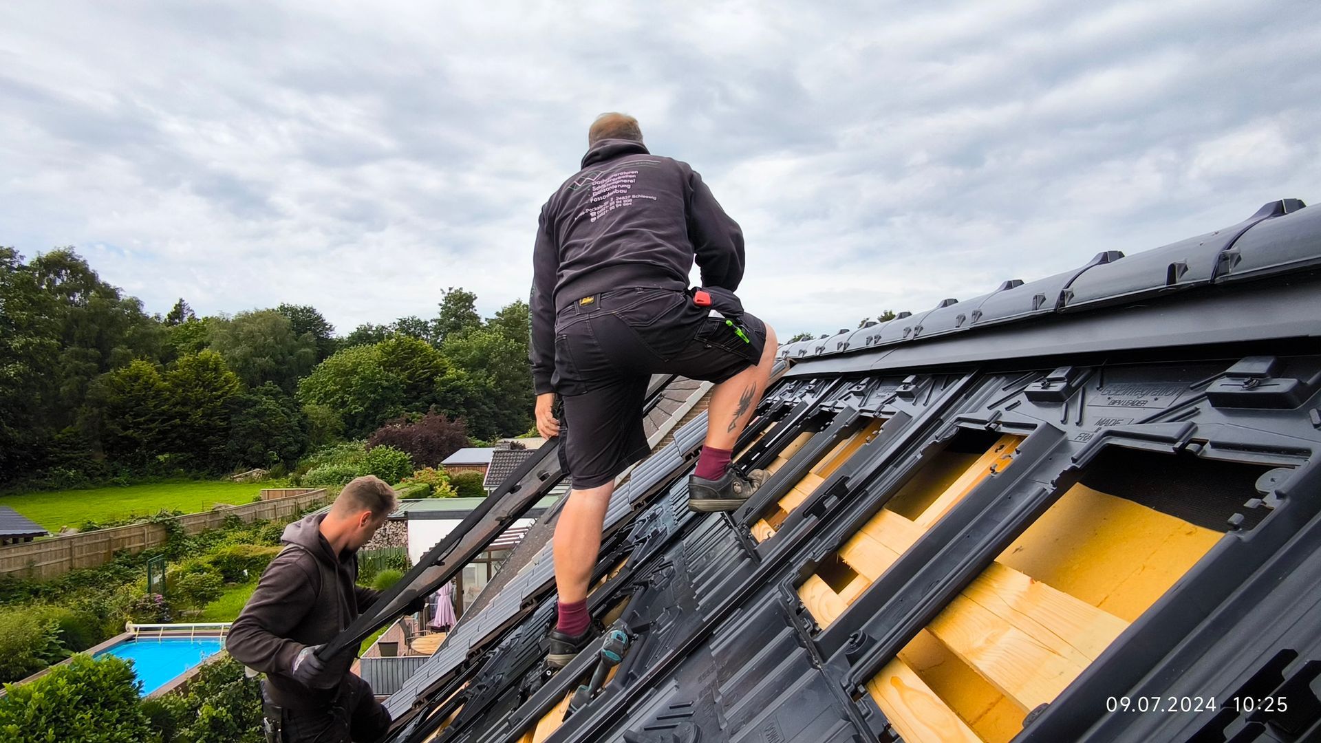 Zwei Männer arbeiten auf dem Dach eines Gebäudes.