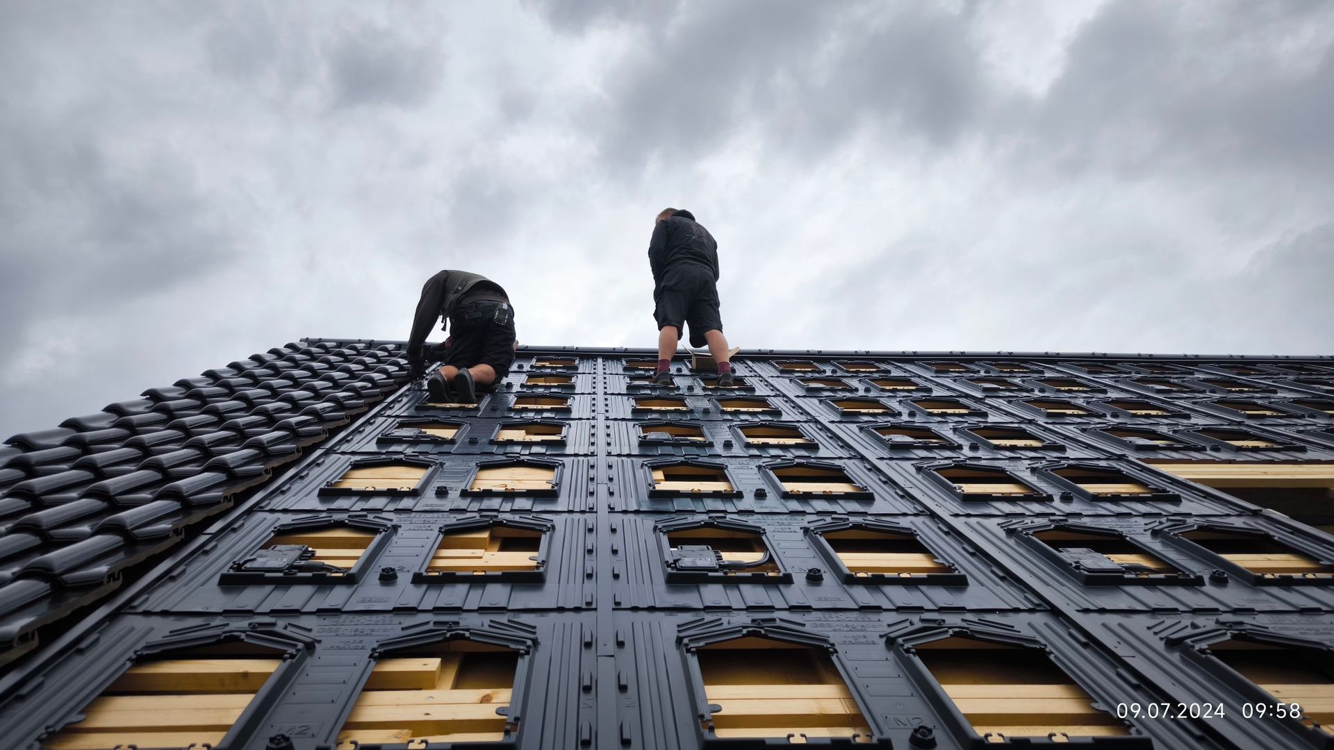 Zwei Männer arbeiten auf dem Dach eines Gebäudes.