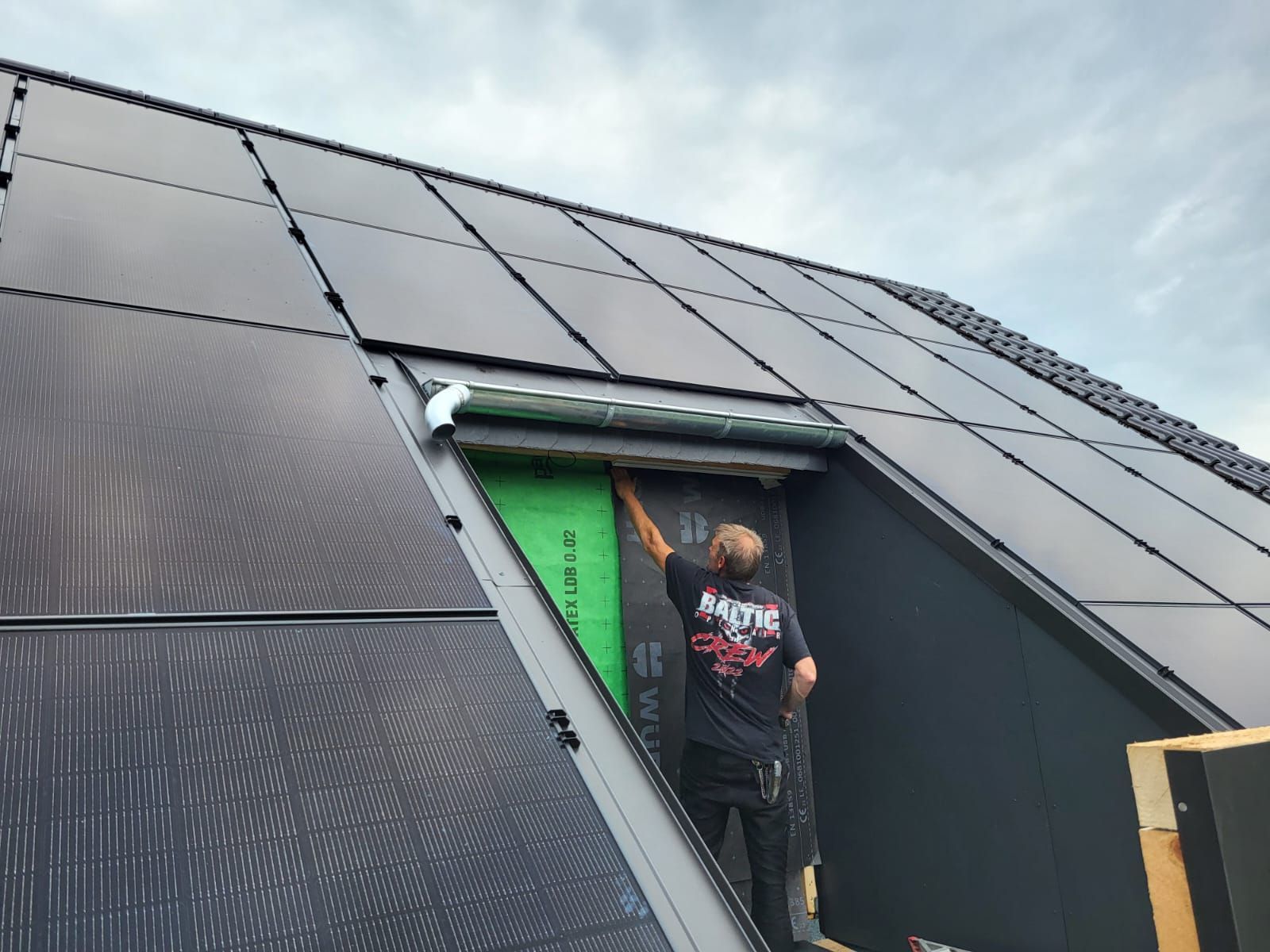 Ein Mann installiert Solarmodule auf dem Dach eines Hauses.