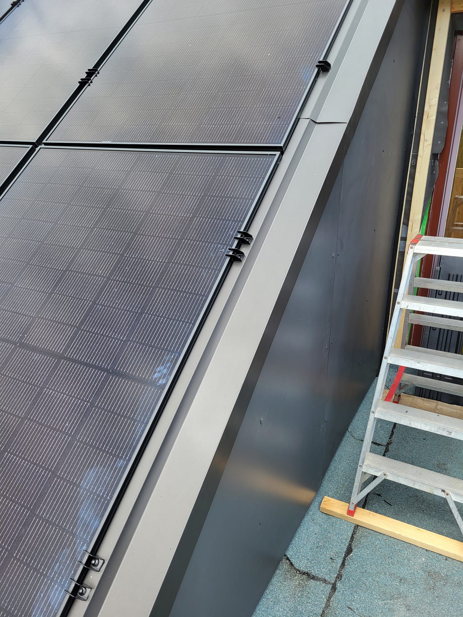 Neben einem Solarpanel an der Seite eines Gebäudes steht eine Leiter.