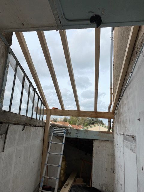 Couloir sur le toit partiellement construit avec poutres apparentes.