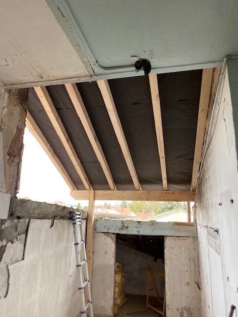 Pièce en construction avec poutres apparentes au plafond.