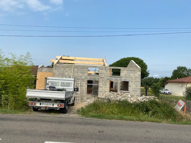 Maison en construction avec un camion blanc garé devant.