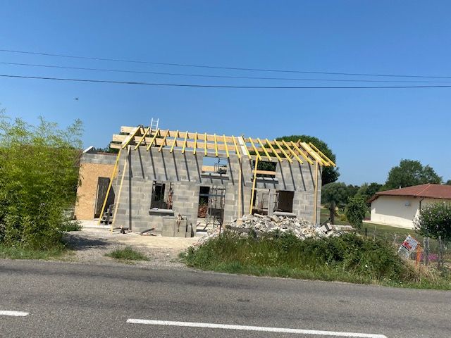 Maison en construction avec la charpente de toit apparente.