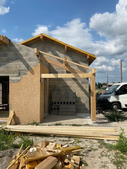 Maison partiellement construite avec ossature bois, murs en pierre et matériaux de construction.