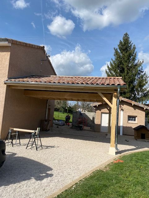 Terrasse couverte attenante à une maison, avec mobilier de jardin, sol gravillonné et pelouse.