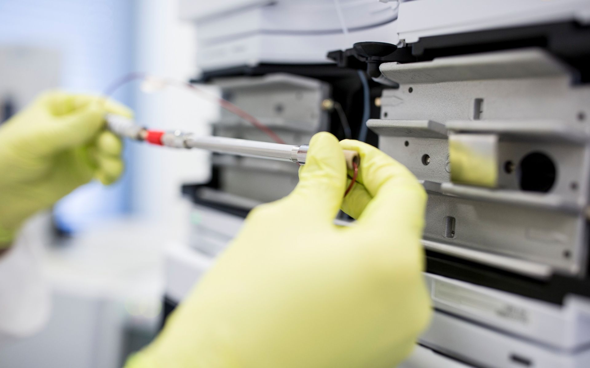 Una persona que lleva guantes amarillos está trabajando en una máquina en un laboratorio.