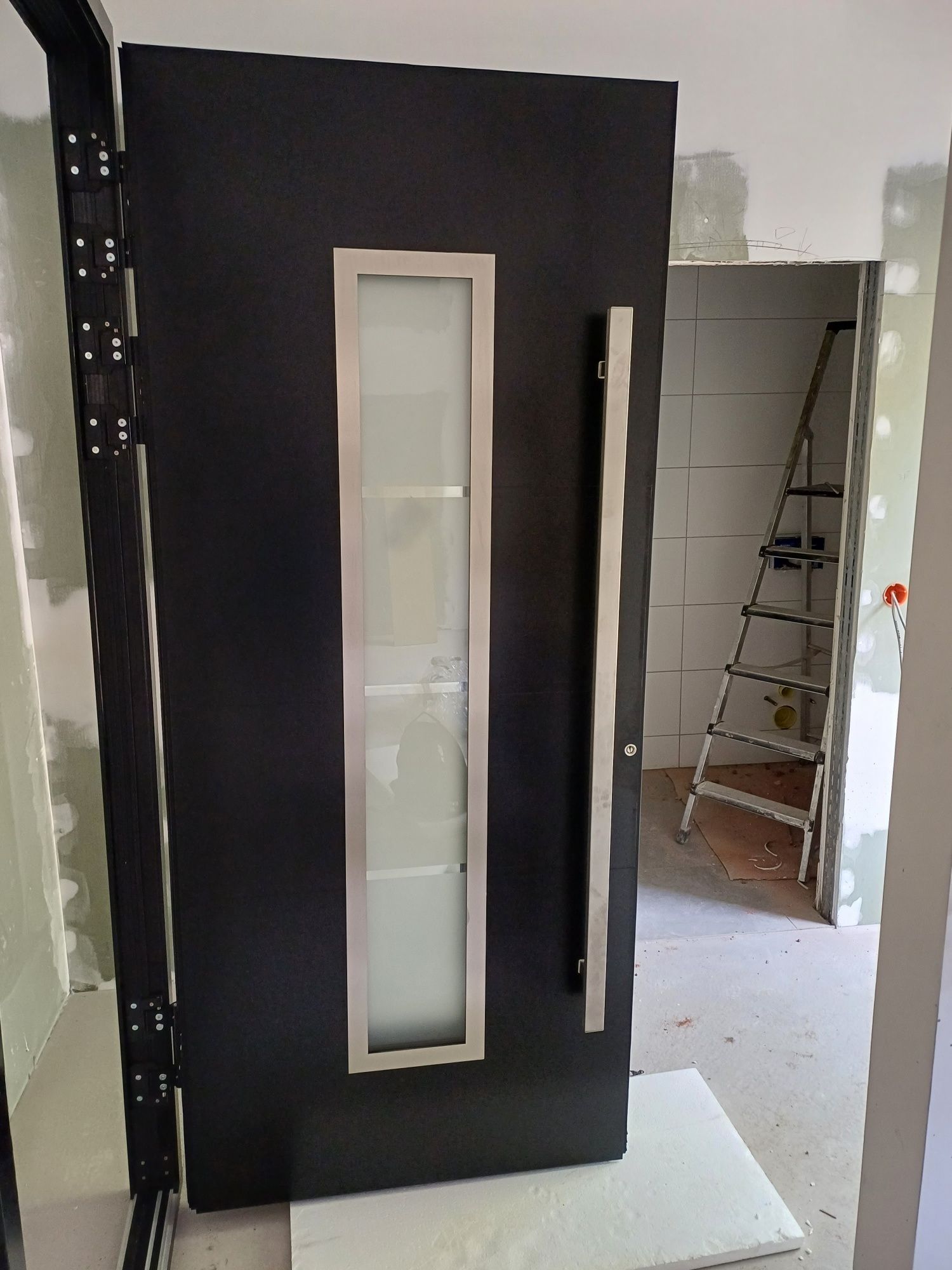 Eine schwarze Tür mit einer Leiter im Hintergrund