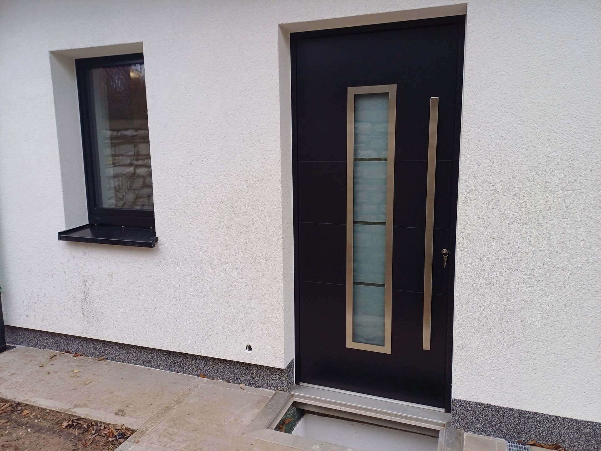 Ein weißes Haus mit einer schwarzen Tür und einem Fenster