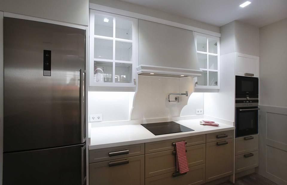 Una cocina con electrodomésticos de acero inoxidable y gabinetes blancos.