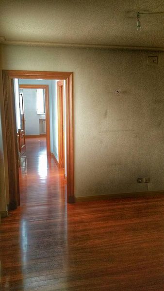 Una habitación vacía con pisos de madera y una puerta que conduce a un pasillo.