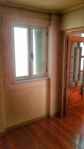 Una habitación vacía con una ventana y una puerta de madera.