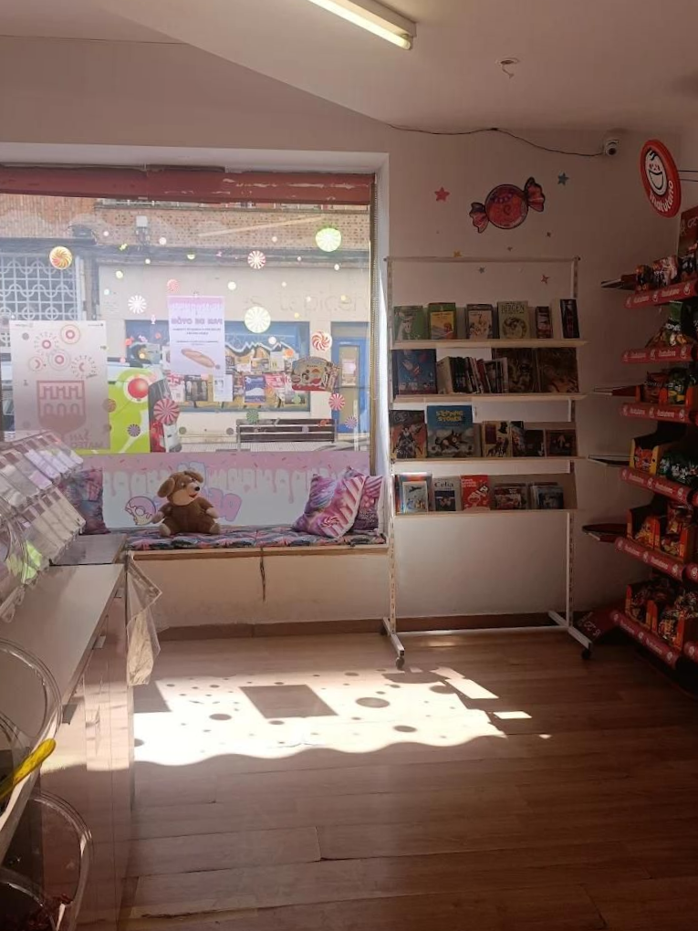Interior de una tienda de dulces: asientos junto a la ventana con almohadas y estantes para dulces.