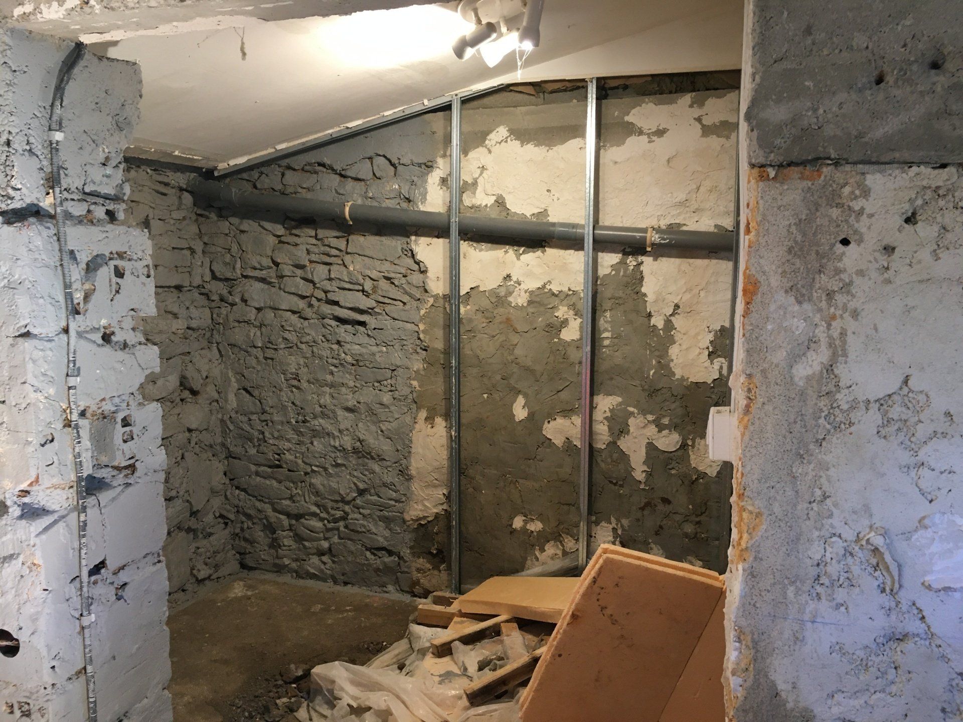 Murs gris en pierre dans une cave avec un tuyau