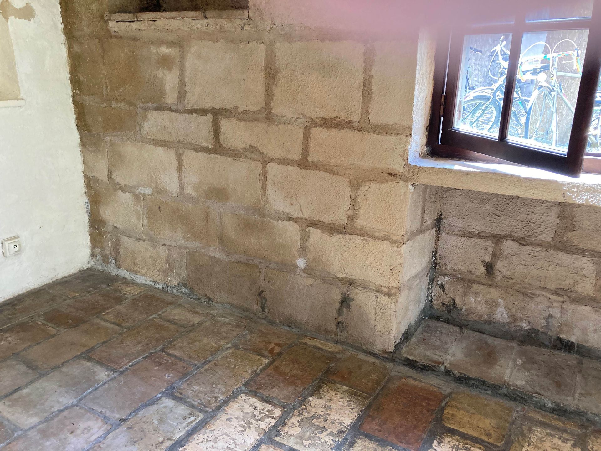 Moisissure sur un mur en pierre et sol en tommettes 